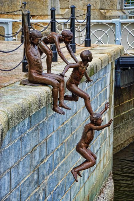 bronze sculptures of people jumping the fence
