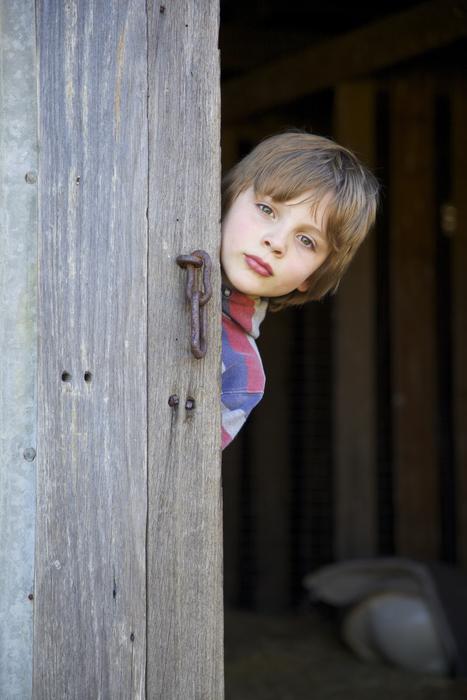 a child peeking out from behind the wall