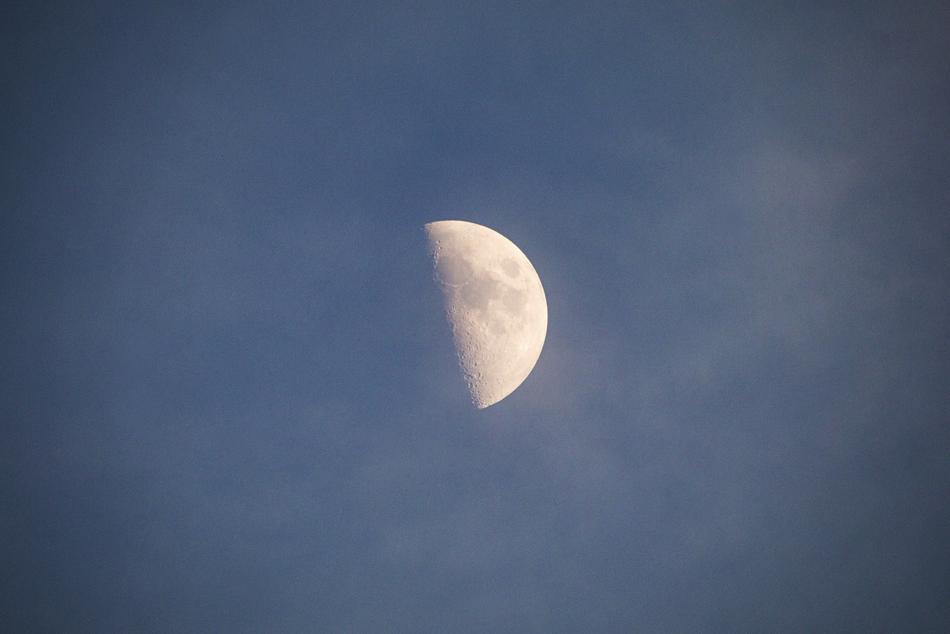 half of the moon in the blue sky