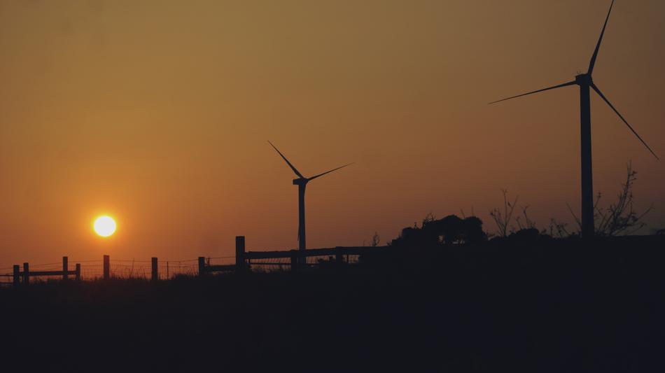 silhouettes of wind turbines at orange dusk