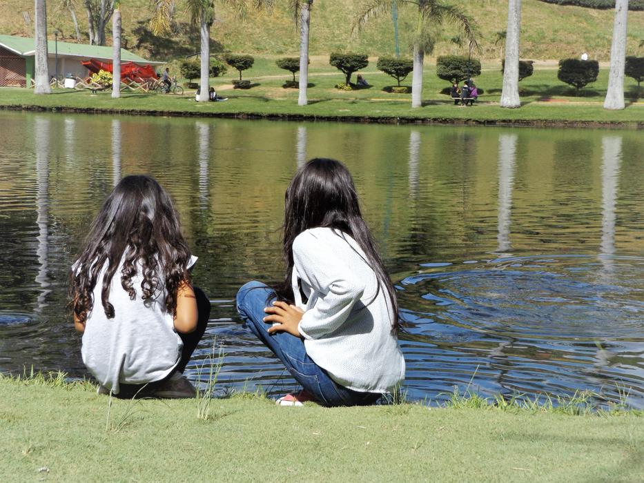 two girls sitting by a lake