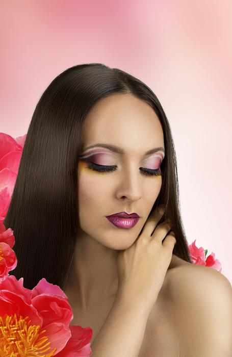 brunette among flowers on a pink background