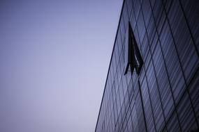 Glass building with open window at blue and white sky background