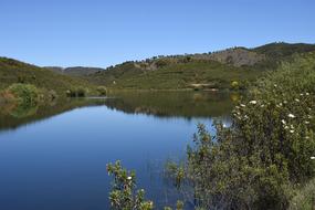 a large lake with green grass and rocks