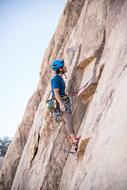 young Man Climbing rock with rope