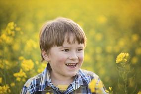 happy caucasian Boy in blooming rape field