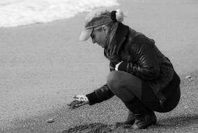 black and white photo of a girl touching sand on the shore of a reservoir in Granada