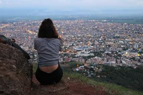 girl makes a panoramic photo of the city from the top of the mountain