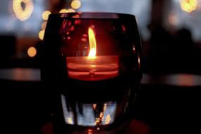 a burning candle in a glass on the table