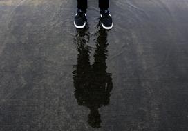 reflection of person in sneakers standing on water