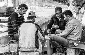 Black and white photo of men playing board games on the chair outdoors