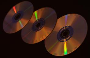 Three shiny compact disks at darkness