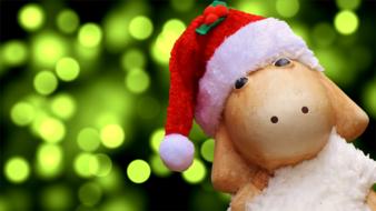 Cute, colorful and beautiful figure of the Christmas sheep with red and white Santa hat, at blurred background with green bokeh lights
