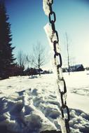 an iron chain in the snow in the trees