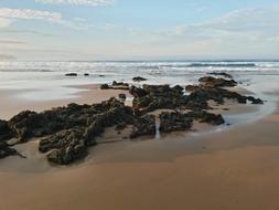 big rocks by the beach with sand