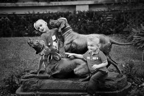 small child Girl and boy posing at hunting dogs sculpture