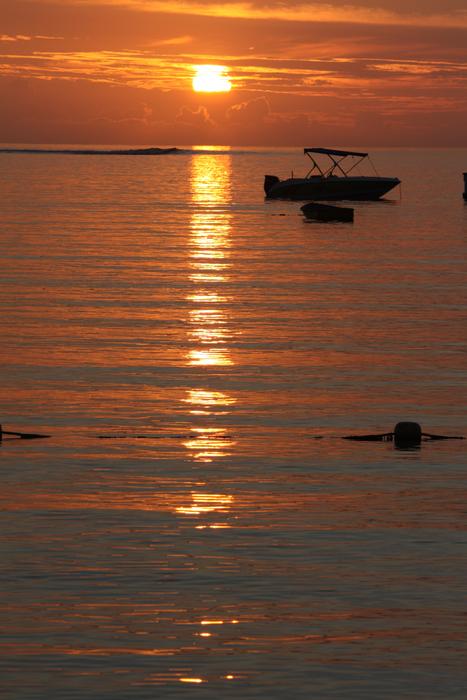 the sun is bright with a road and a boat