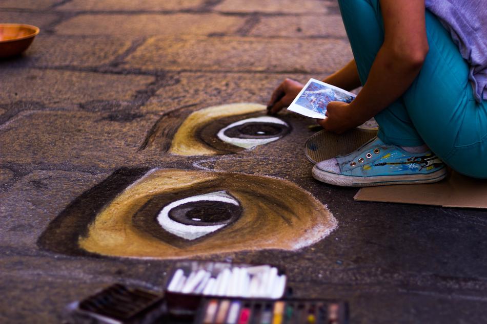 Artist drawing eyes on the pavement