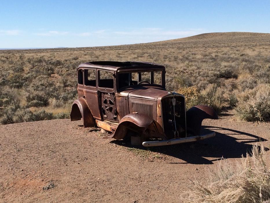 a rusty, forgotten car in the sand