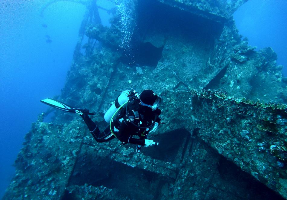 a man floating in the water near an old ship