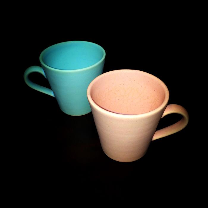 colored mugs on a black background