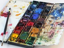Colorful and beautiful watercolour paint with the paint splatter on the box, and brush