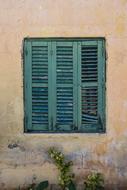 windows with wooden green shutters on the facade of an old house