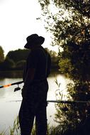 silhouette of a fisherman by the lake
