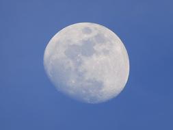 A full white moon in a blue sky