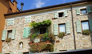 the stone wall of the house with windows