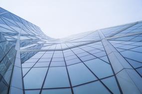 Low angle shot of the shiny glass building with the reflections, in light