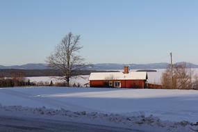 red cottage on waterside at snowy winter, sweden, tallberg