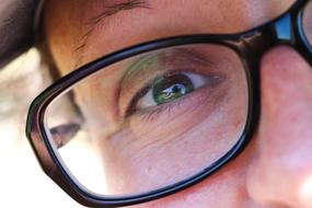 Close-up of the person's green eye in glasses