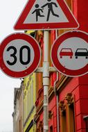 three traffic signs on pole at facade