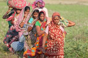 Indian women walk on green grass