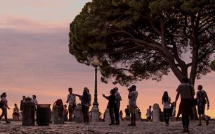 Tourists, near the tree, in Lisbon, Portugal, at colorful and beautiful sunset in the sky