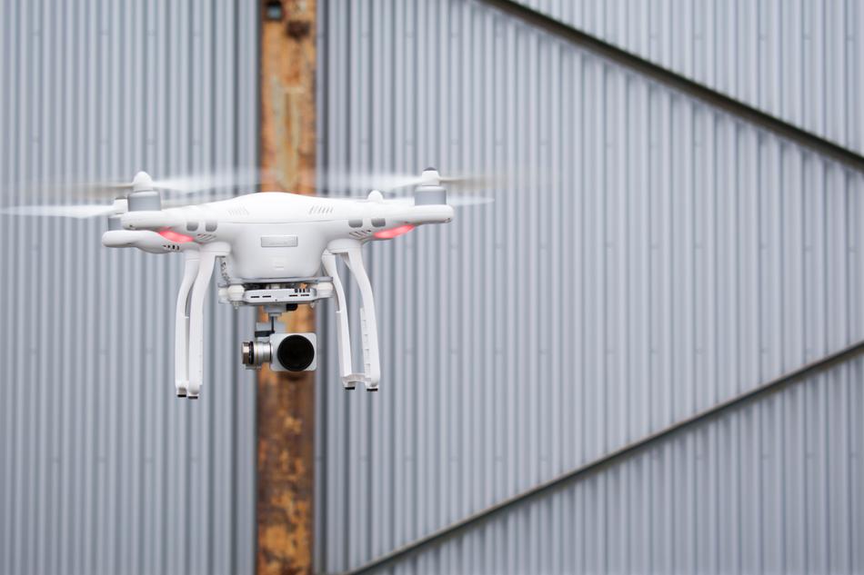 white quadcopter with camera near the fence
