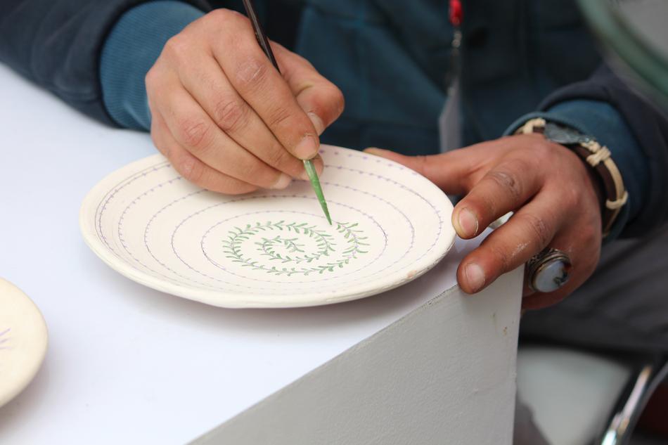 Person, painting on the beautiful plate, with green paint
