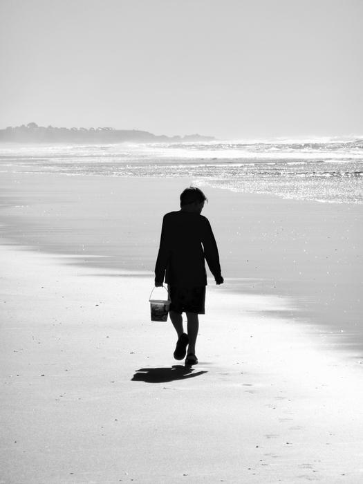 woman with a bag walking along the beach