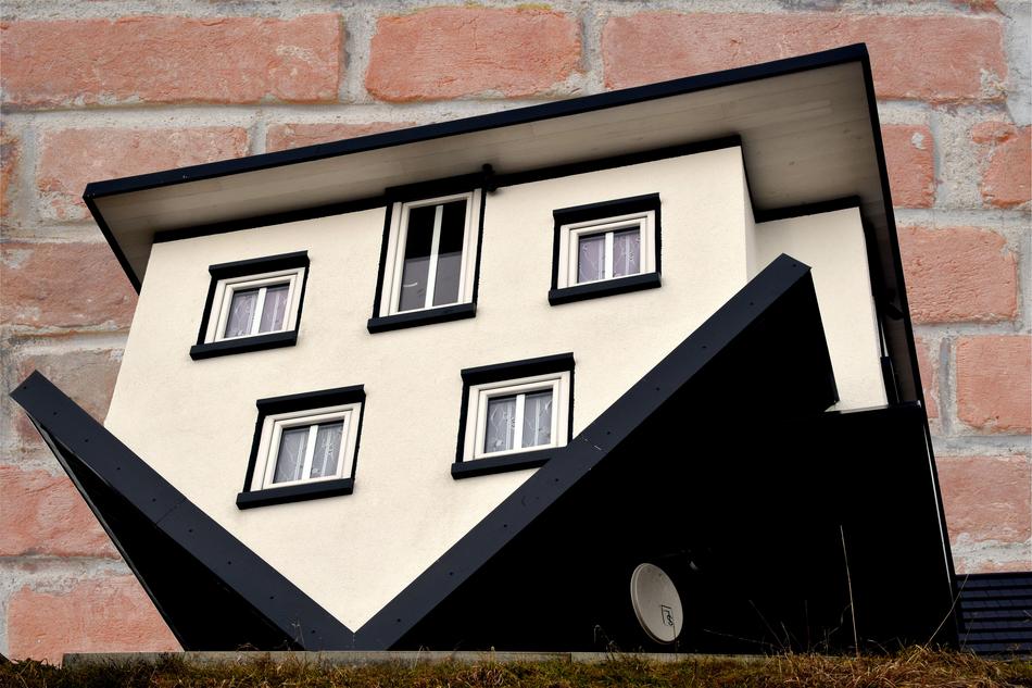 concept of topsy-turvy House at brick wall