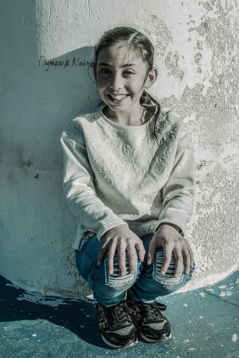 Smiling child Girl sits at wall