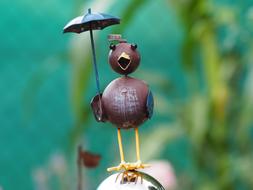 metal figurine of a bird with an umbrella in the garden