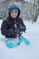 Boy making snowballs in snow in winter