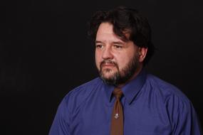 photo of a man in a blue shirt with a brown tie