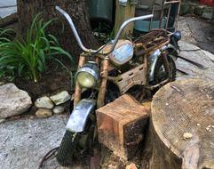 the bicycle is standing by the log