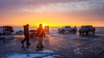 people on the ice with cars