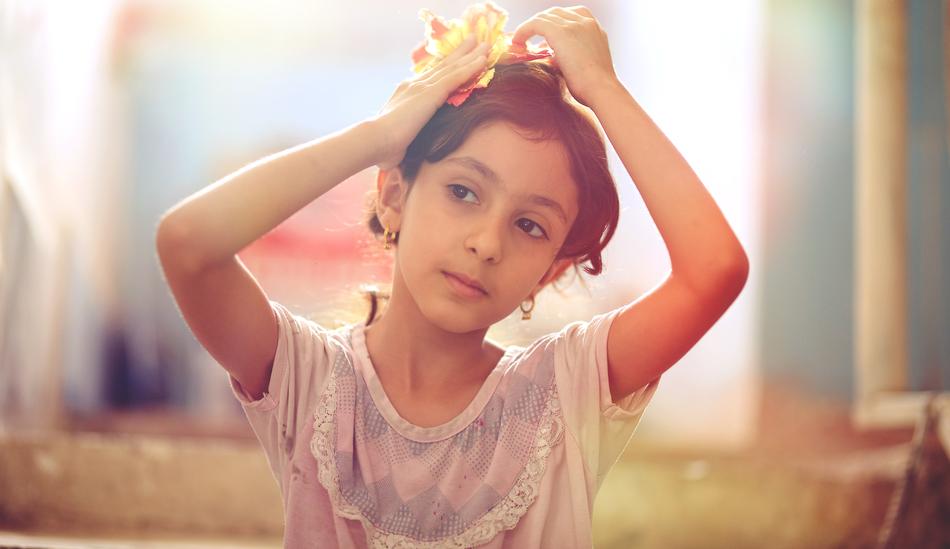 Iraqi girl decorates hair with yellow and red flower in summer
