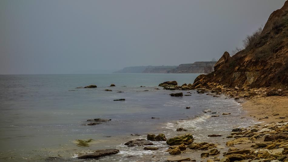 stone beach in the sea with mountains