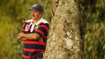 a man in a striped t-shirt stands near a tree