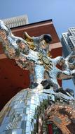 Beautiful, shiny, mirrored statue of the bird, under the blue sky